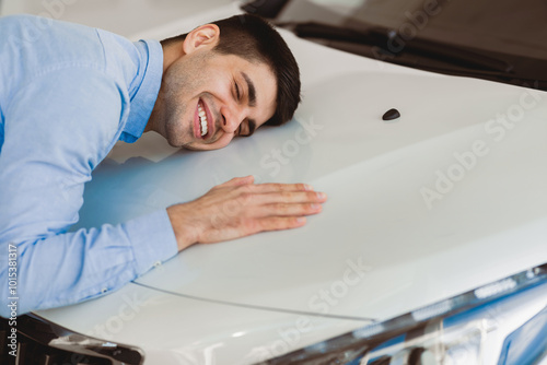 New Car Owner. Happy Man Touching Hugging His Brand-New Auto Cherfully Buying Vehicle In Auto Dealership Store photo