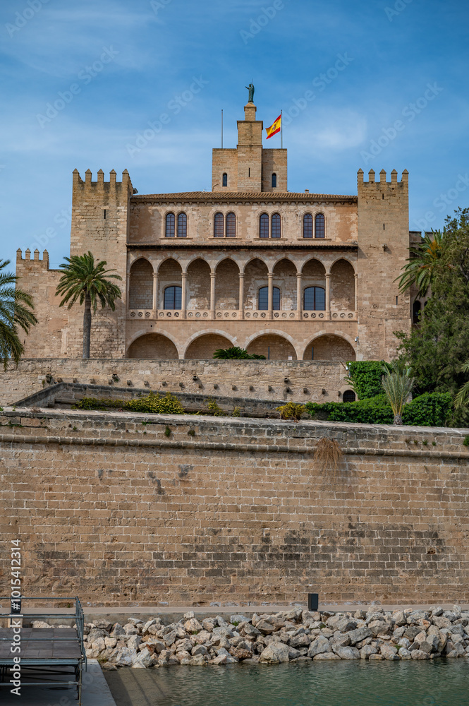 Fototapeta premium The Royal Palace of La Almudaina in Palma de mallorca with trees and lake in front, vertical shot, Majorca