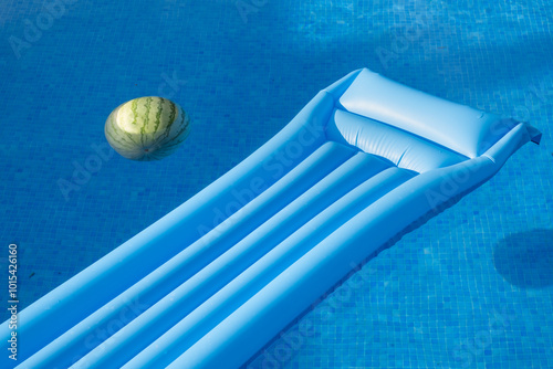 A surreal and creative close-up scene of an inflatable mat and a watermelon floating on the water of a pool. Abstract, unreal and dreamy background photo