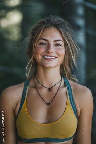 A woman with long brown hair and a yellow tank top is smiling. She is wearing a necklace and a bracelet