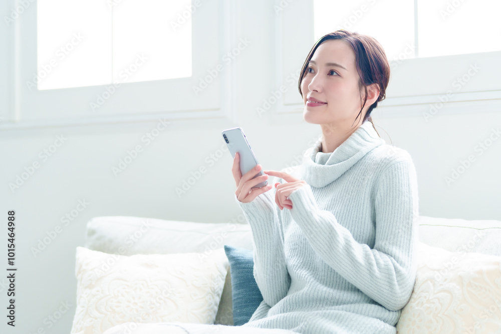 リビングでスマートフォンを使う女性