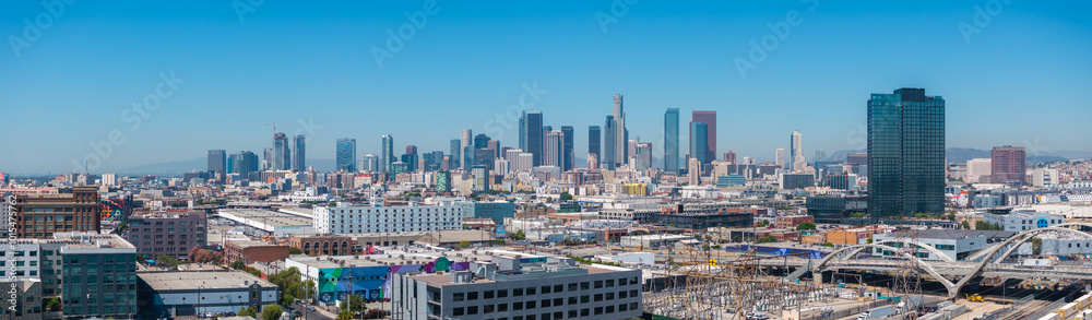 Panoramic aerial view of downtown Los Angeles with skyscrapers, including U.S. Bank Tower, and the Sixth Street Viaduct under a clear blue sky. Panoramic aerial view of downtown Los Angeles with skyscrapers, including U.S. Bank Tower, and the Sixth Street Viaduct under a clear blue sky.