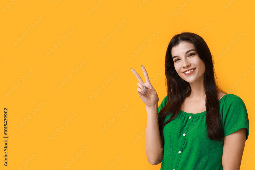 Young woman showing peace sign on yellow background Young woman showing peace sign on yellow background