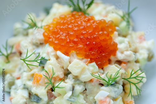 Delicious olivier salad with red caviar and dill on white plate, perfect for festive meals. Vibrant colors and textures capture traditional russian cuisine