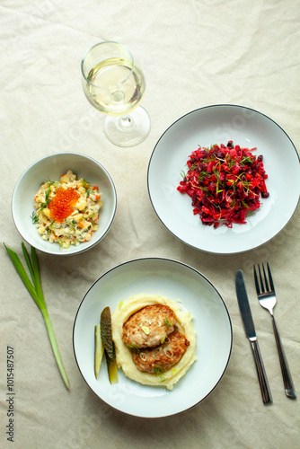 Wallpaper Mural Top view of a traditional russian dinner on a beige tablecloth, featuring cutlets, mashed potatoes, vinaigrette, olivier salad, and white wine, perfect for a cozy night in Torontodigital.ca