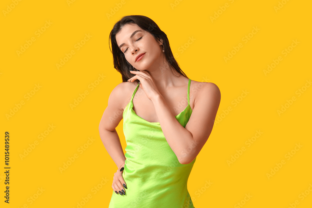 Beautiful young woman in stylish green dress on yellow background Beautiful young woman in stylish green dress on yellow background