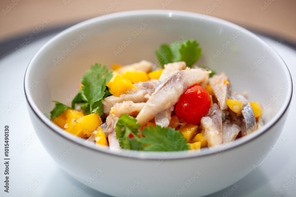 Fresh ceviche served in a white bowl with slices of fish, mango, cherry tomato, and garnished with cilantro Fresh ceviche served in a white bowl with slices of fish, mango, cherry tomato, and garnished with cilantro