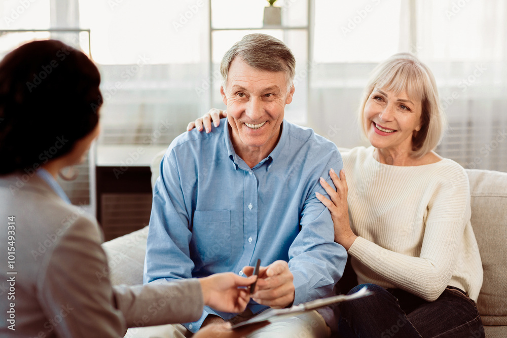Insurance Concept. Happy senior couple consulting with female agent at home, signing papers