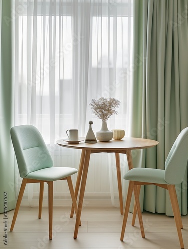 Round wooden table with green chairs against window with white curtains. White vase with flowers, cup on table. Green walls, wood floor, natural in modern Scandinavian dining room interior.