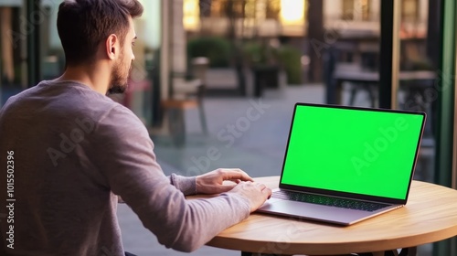 Focused man working on laptop with green screen showcasing home office setup and digital creativity perfect for business and technology themes