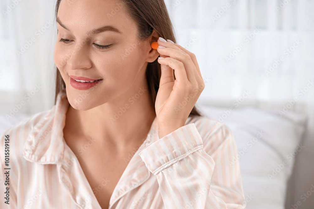 Young woman putting ear plug in bedroom, closeup Young woman putting ear plug in bedroom, closeup