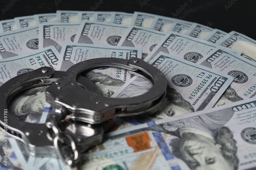 Corruption. Handcuffs and dollar banknotes on black table, closeup Corruption. Handcuffs and dollar banknotes on black table, closeup