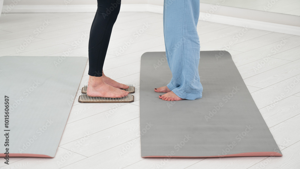 Caucasian woman stands on sadhu boards with therapist support.