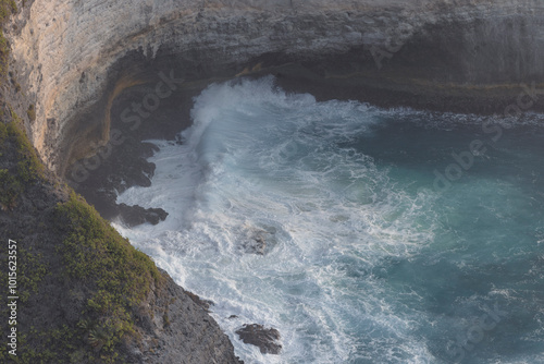 A view from above of Kelingking Beach on Nusa Penida, Indonesia, reveals a stunning landscape where crystal-clear turquoise waters meet white sandy shores. photo