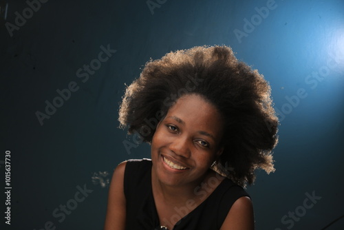 Headhoot of an African American Lady in a black dress smiling and she is more than pretty with natural black hair