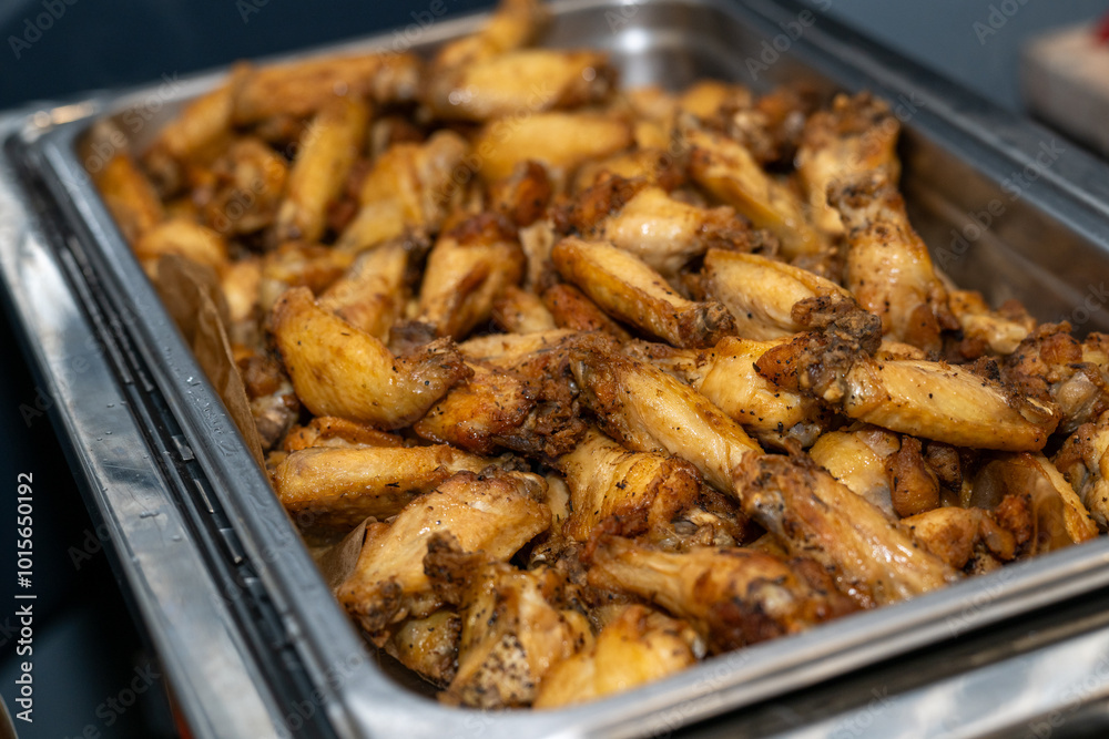 Grilled chicken wings in a metal catering tray served at a party Grilled chicken wings in a metal catering tray served at a party