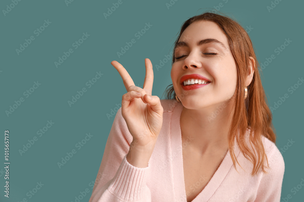 Pretty young woman showing peace gesture on blue background, closeup Pretty young woman showing peace gesture on blue background, closeup