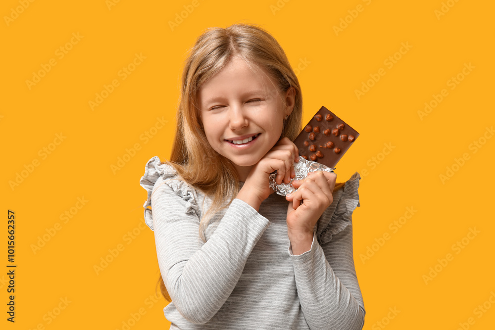 Cute little girl with sweet chocolate bar on yellow background Cute little girl with sweet chocolate bar on yellow background