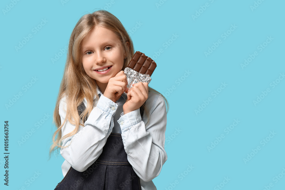 Cute little girl with sweet chocolate bar on blue background Cute little girl with sweet chocolate bar on blue background