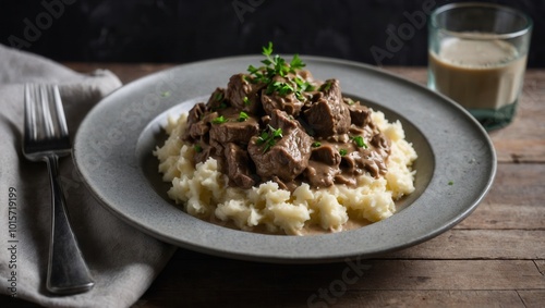 Close-up of mashed potatoes and meat dish with gravy and herbs on a rustic table