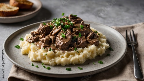 Plate of mashed potatoes with meat-based gravy and herbs, rustic culinary presentation