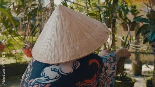 Asian person in conical hat working in the garden. photo