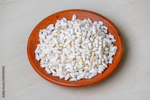 Popped rice or Khoi, served on a clay plate on a wooden background. It is traditional and popular Bengali snack. photo