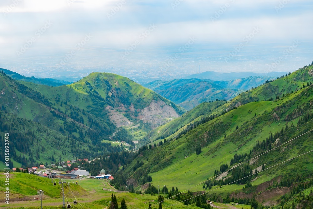 Fototapeta premium Photo of a Valley in summer with forest, mountains, snow, fog and clouds