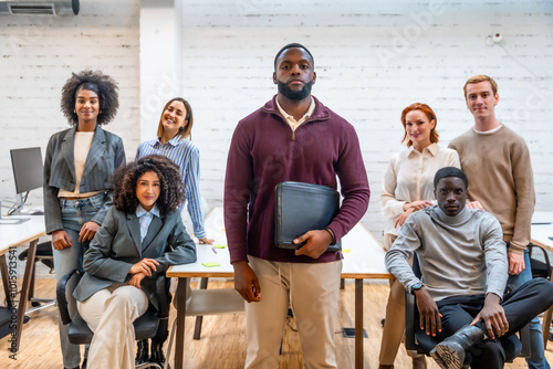 African man standing in a coworking surrounded by colleagues