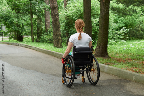 Back view of woman using wheelchair walking outdoors