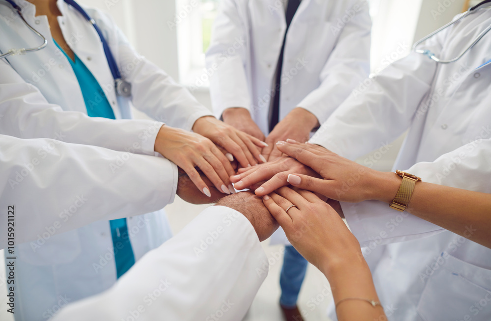 Team of doctors in white uniform standing in hospital or clinic putting their arms in a pile. Stack of medical staff hands. The concept of unity, partnership, teamwork and health care .