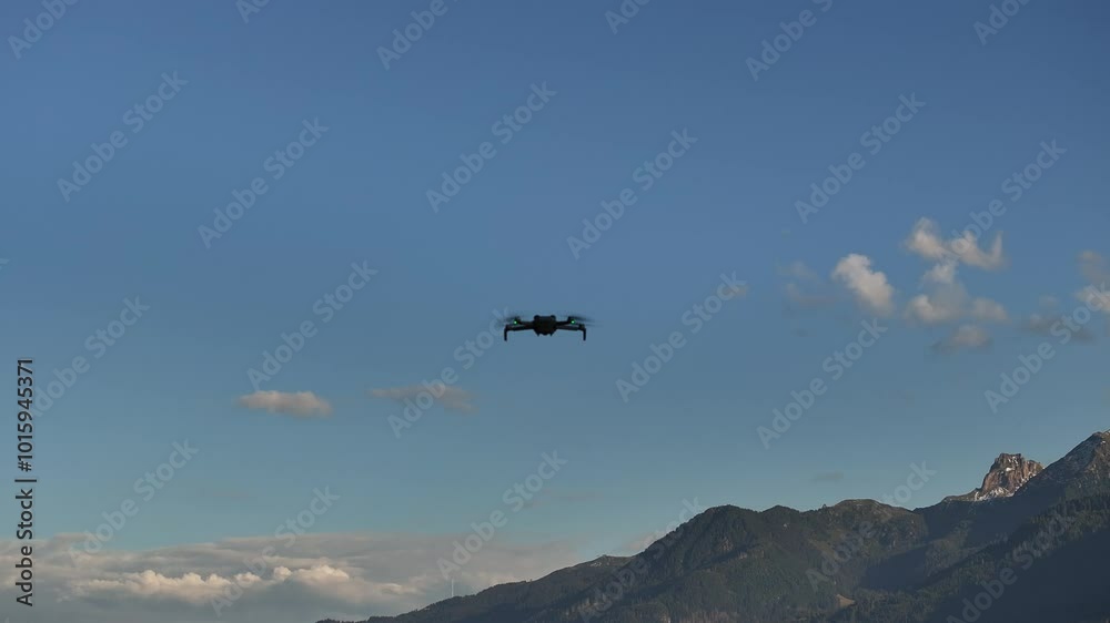 drone flies against a clear blue sky, with mountain peaks faintly visible in the background drone flies against a clear blue sky, with mountain peaks faintly visible in the background