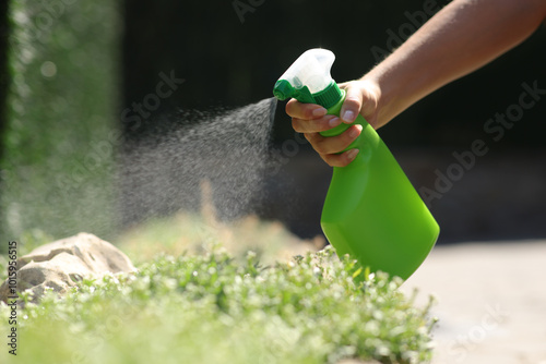 Woman hand spraying insecticide over plants in a garden