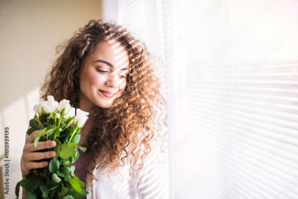Portrait of beautiful young woman with curly hair looking at bouquet of white roses. Portrait of beautiful young woman with curly hair looking at bouquet of white roses.