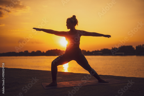 Woman practicing yoga in sunset. Virabhadrasana, Warrior 2 pose. photo