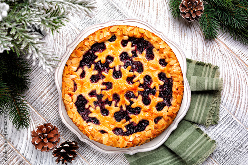 Baked mixed berry crust pie or tart with snawflakes decoration. Homemade. Winter Christmas or New Year festive bakery, wooden white table surface, top view. photo