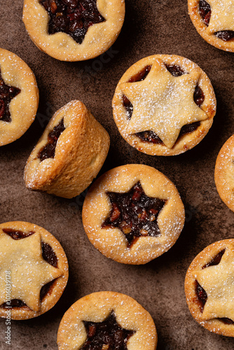 Background with Traditional british christmas Mince pies on a brown plate, sprinkled with sugar. Also called mincemeat or fruit pie, filled with a mixture of fruit, spices and suet. Vertical image.