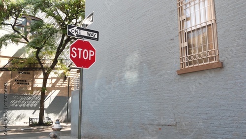 New York City oneway crossroad, Minetta street intersection one way arrow. Manhattan Greenwich Village residential building architecture, NYC United States. Blue brick wall, window, red stop road sign photo