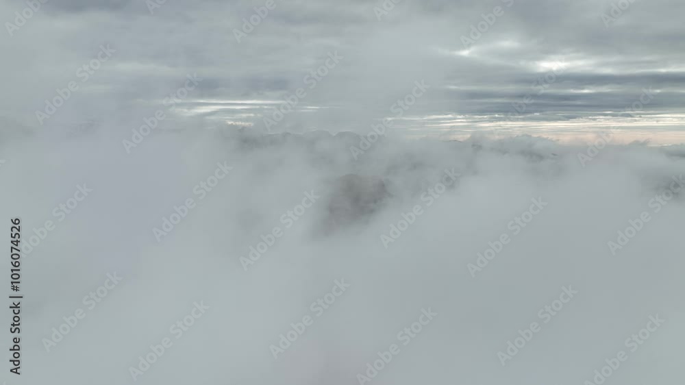 Aerial view of mountain peaks emerging through thick clouds at Hafursey, Iceland, creating a dramatic and serene scene under a cloudy sky. Aerial view of mountain peaks emerging through thick clouds at Hafursey, Iceland, creating a dramatic and serene scene under a cloudy sky.