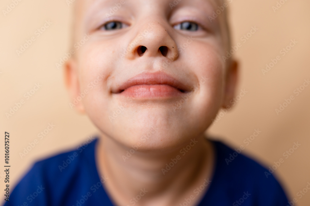 A cheerful young boy with a playful expression poses against a simple background, evoking joy and innocence in an indoor setting A cheerful young boy with a playful expression poses against a simple background, evoking joy and innocence in an indoor setting