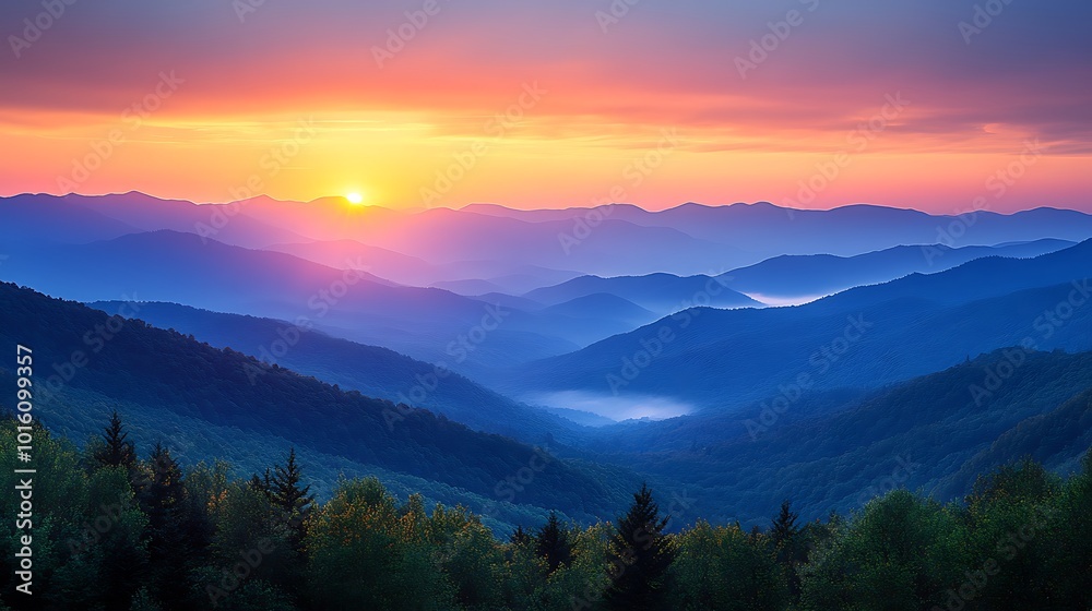 Obraz premium A breathtaking sunrise over a mountain range with a soft haze and fog in the valleys.