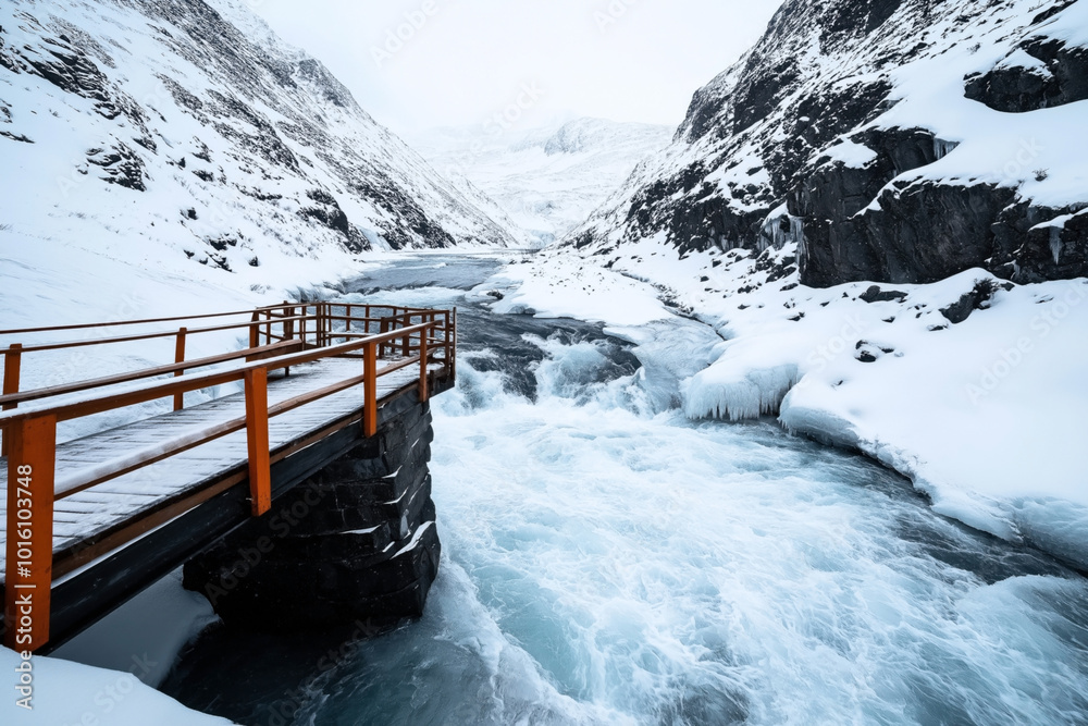 Φωτογραφία Snow-covered mountains with a wooden bridge over a turbulent river in a winter landscape, featuring icy banks and frozen waterfalls