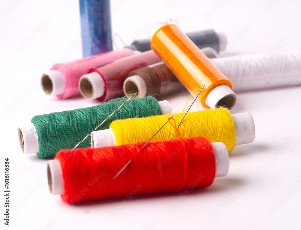 Colorful sewing thread set and needles isolated on background.
