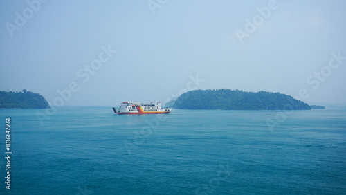 LAMPUNG - INDONESIA, 07-September-2024 : Commercial ferry ships carrying passengers against the backdrop of the blue sea and small uninhabited islands photo