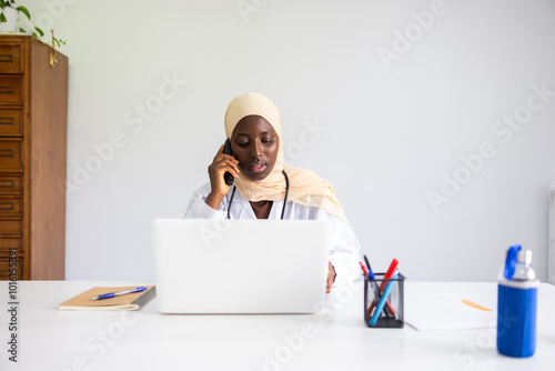 Black female doctor with hijab consulting on phone