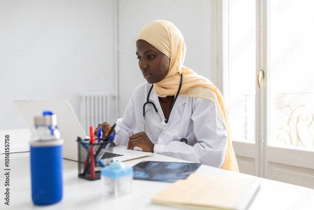 Black female doctor in hijab working at her desk Black female doctor in hijab working at her desk