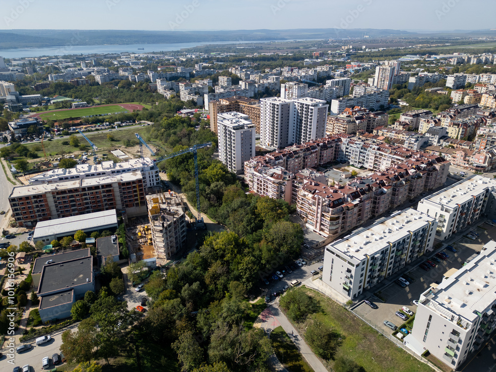 Obraz premium Aerial view of a densely populated urban area with tall residential buildings, colorful architecture, and parking lots. The cityscape showcases modern living in a busy neighborhood. Bulgaria, Varna