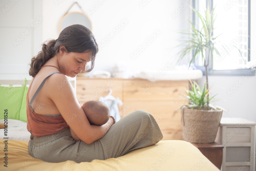 A woman is holding a baby while sitting on a bed A woman is holding a baby while sitting on a bed