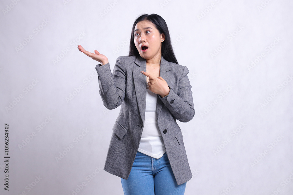 expression of adult beautiful woman surprised hand pointing, presenting, look to the right wearing gray suit and jeans standing isolated on white background. for advertising content, fashion, magazine expression of adult beautiful woman surprised hand pointing, presenting, look to the right wearing gray suit and jeans standing isolated on white background. for advertising content, fashion, magazine