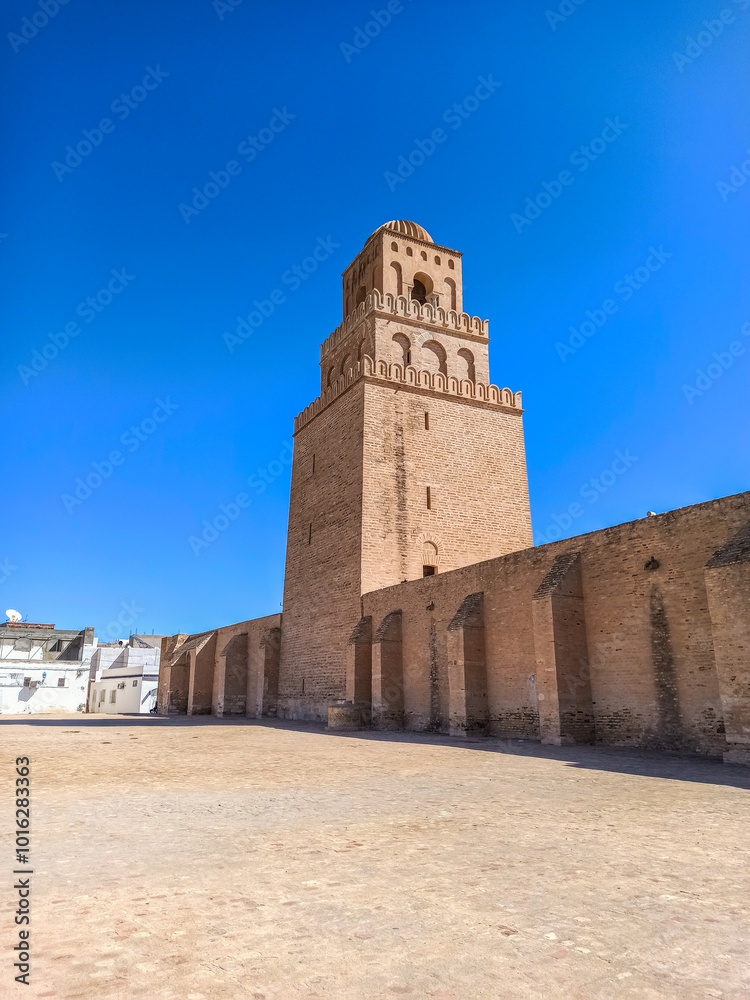 Obraz premium The Great Mosque of Kairouan, also known as the Mosque of Uqba, is a significant Islamic landmark built in the 7th century. It features an ancient minaret, marble columns, and beautiful domes. 